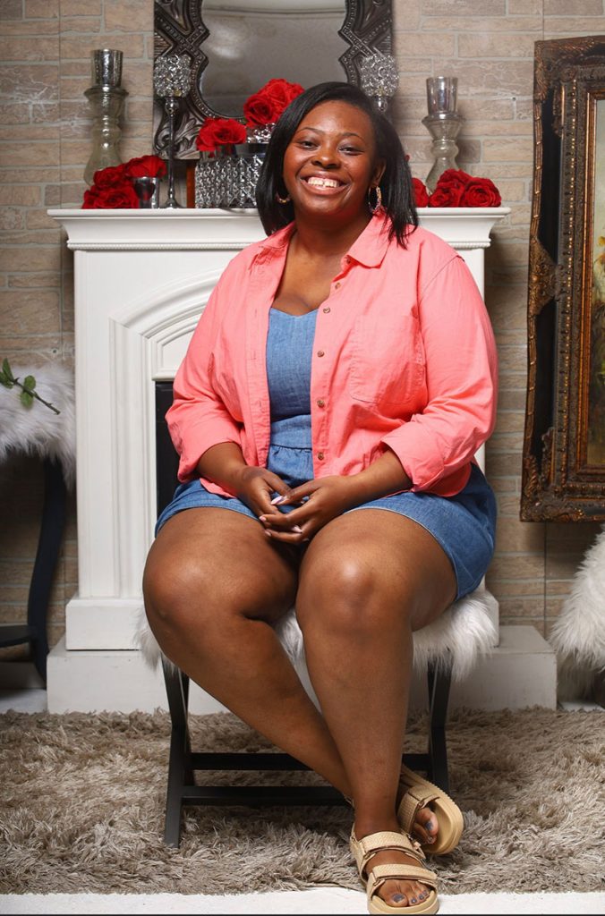 A teen sits in a decorated photo studio and poses for a picture