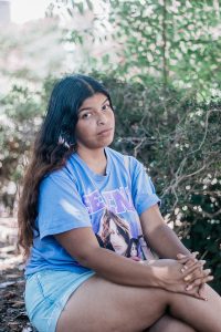 A teen in a blue outfit sits outside