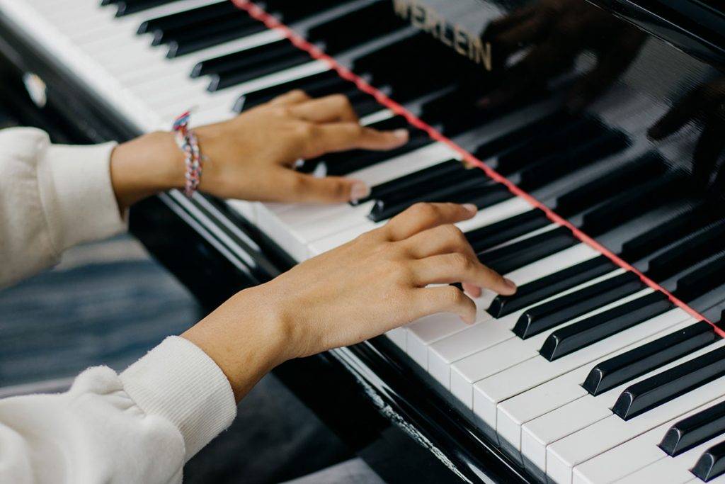 A closeup of a pair of hands on the keys of a piano