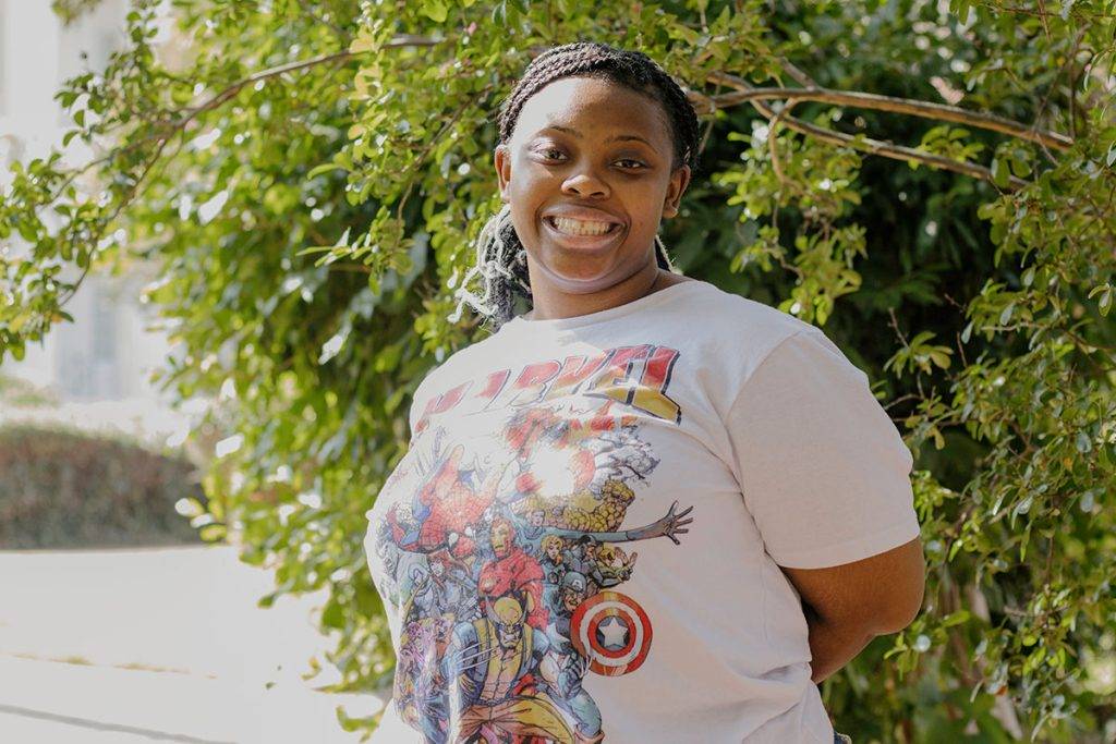 A teen stands outside in the sunlight wearing a Marvel tshirt