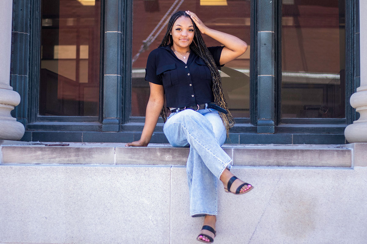 A young teen sits in the windowsill of a marble building