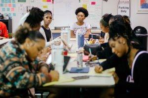 Students sit around a table, writing