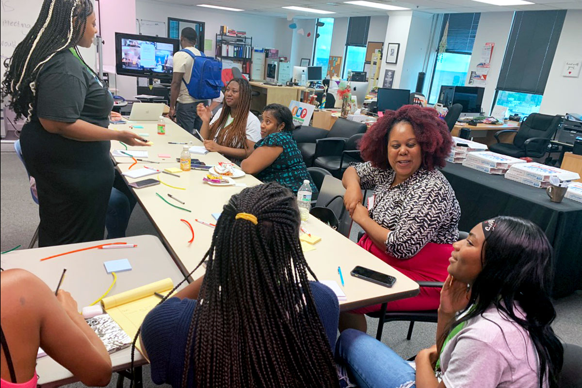 Teens and adults talk around a table